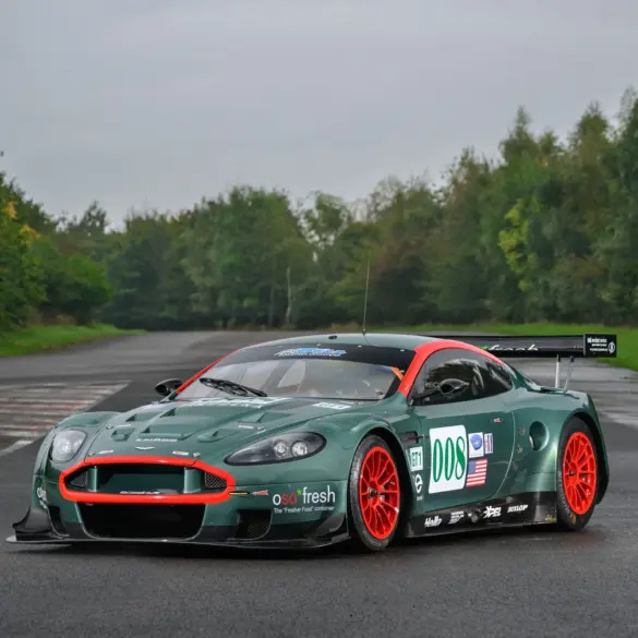 Aston Martin DBR9/5 Rennwagen von 2006 in Grün mit roten Akzenten und Startnummer 008, fotografiert auf einer asphaltierten Strecke.