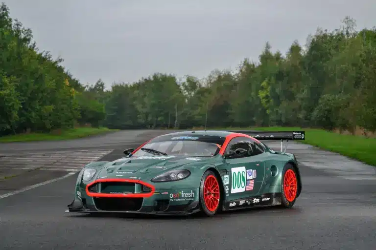 Aston Martin DBR9/5 Rennwagen von 2006 in Grün mit roten Akzenten und Startnummer 008, fotografiert auf einer asphaltierten Strecke.