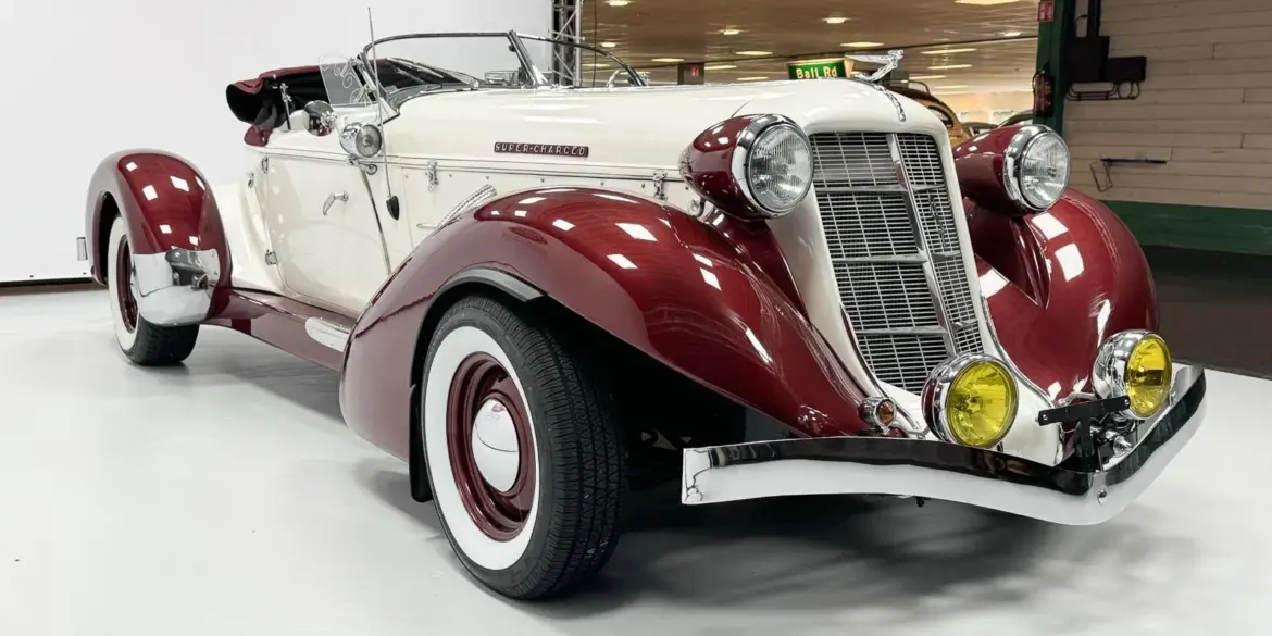 Auburn Speedster 6,7 V8 Cabriolet von 1979 in Weiß mit bordeauxfarbenen Kotflügeln und Chromdetails in einer Halle.