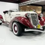 Auburn Speedster 6,7 V8 Cabriolet von 1979 in Weiß mit bordeauxfarbenen Kotflügeln und Chromdetails in einer Halle.