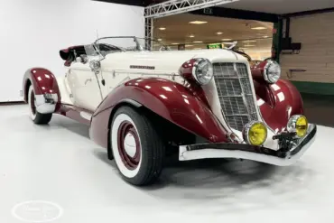Auburn Speedster 6,7 V8 Cabriolet von 1979 in Weiß mit bordeauxfarbenen Kotflügeln und Chromdetails in einer Halle.