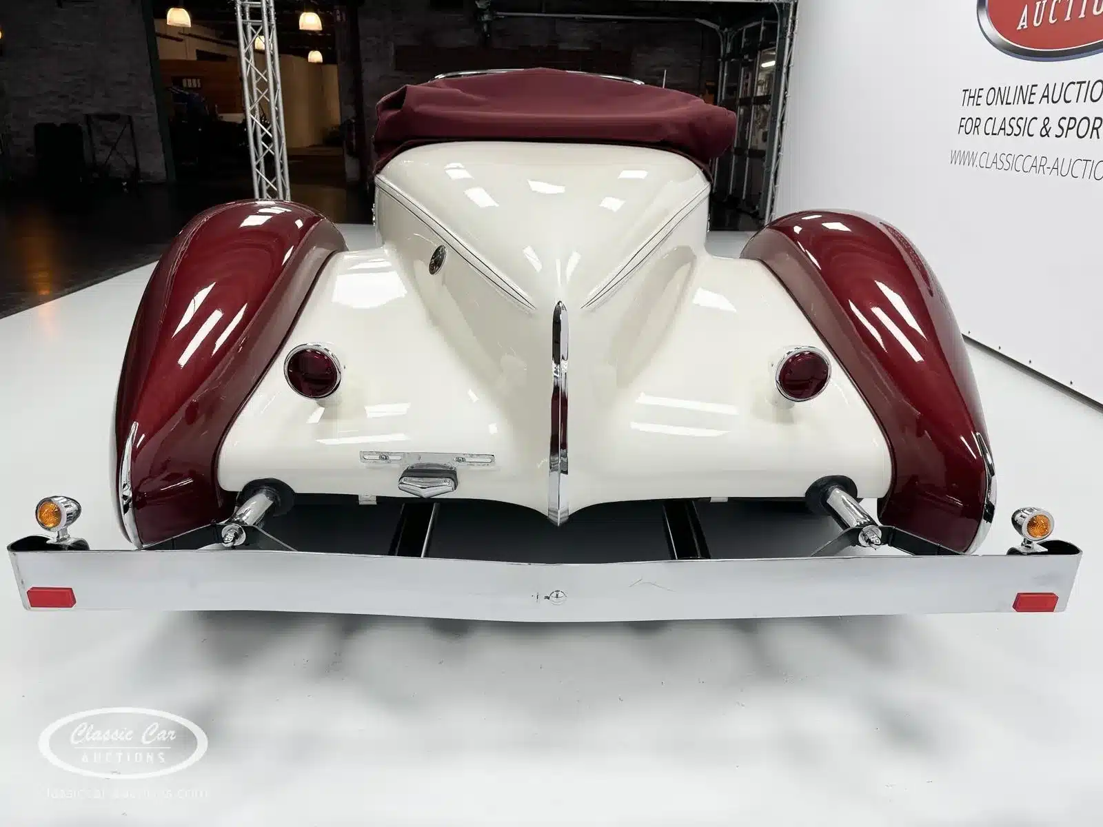 Auburn Speedster 6,7 V8 von 1979, Heckansicht mit Boattail-Design, weinrote Kotflügel, weißes Cabrioverdeck.