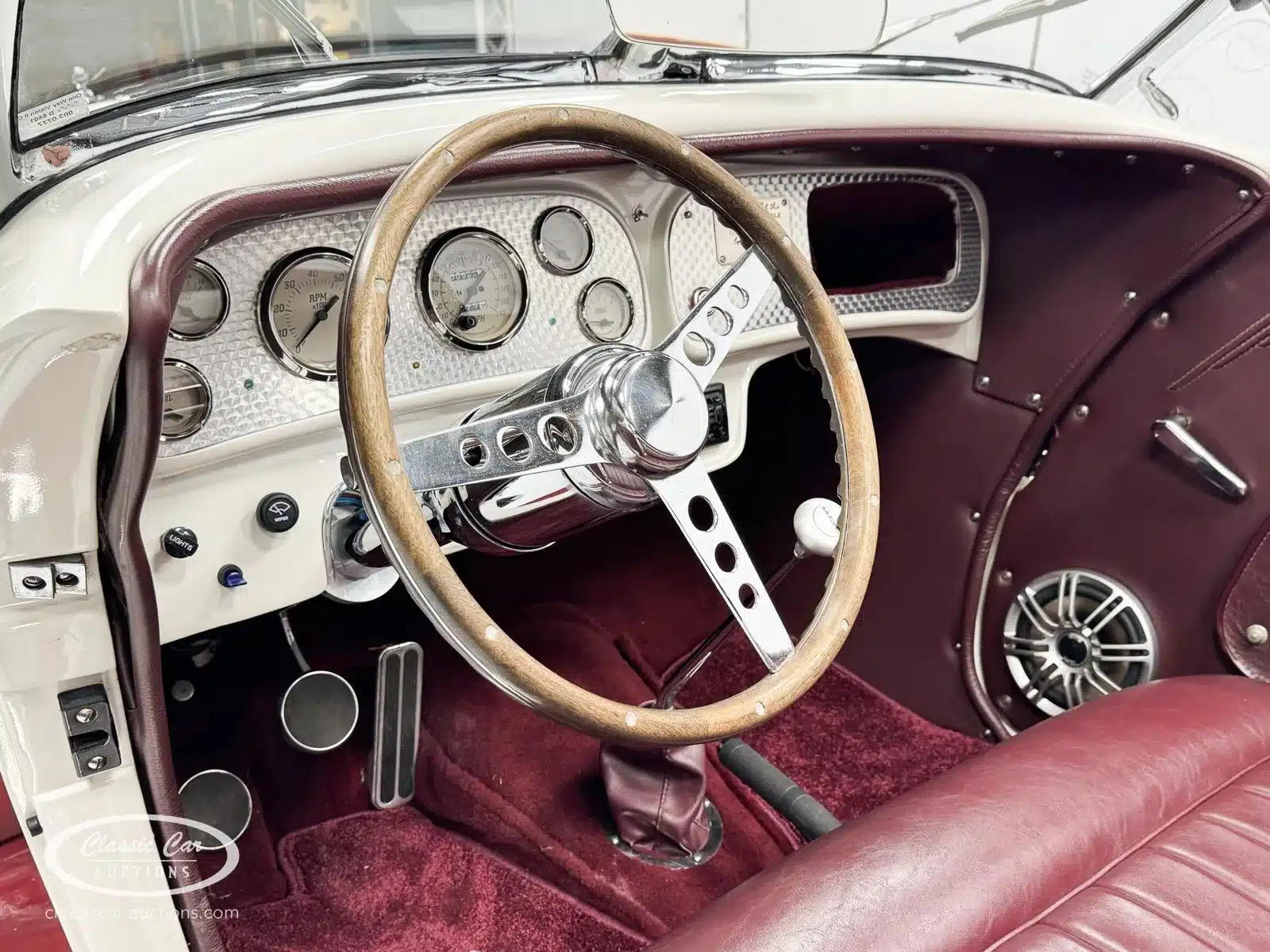 Cockpit und Lenkrad eines Auburn Speedster 6,7 V8 von 1979 mit Holzlenkrad, klassischen Rundinstrumenten und weinroter Lederausstattung.