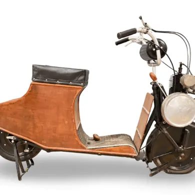 Der 1920 Autoglider 250cc Scooter in kompletter Seitenansicht, mit dreilagiger Holzverkleidung und sichtbarem Zweitaktmotor.