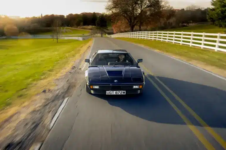 BMW M1 E26 von 1980 in seltener blauer Lackierung fährt auf einer Landstraße.