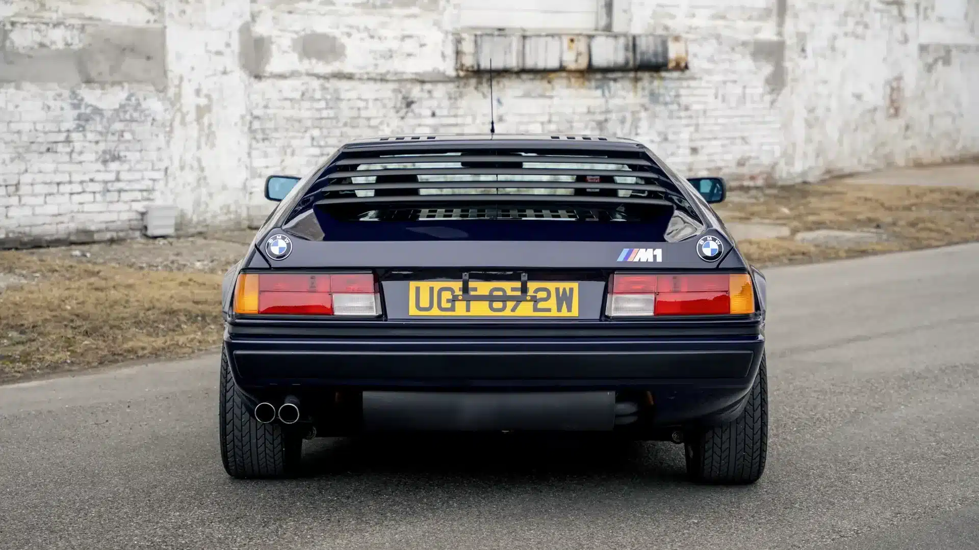 BMW M1, Baujahr 1980, seltene originale Heckansicht mit britischem Kennzeichen vor einer Mauer