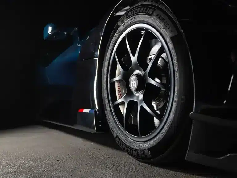 Detailansicht eines Bugatti Bolide Vorderrads mit Michelin-Reifen und Brembo-Bremsanlage, Teil der Carbon-Karosserie sichtbar.