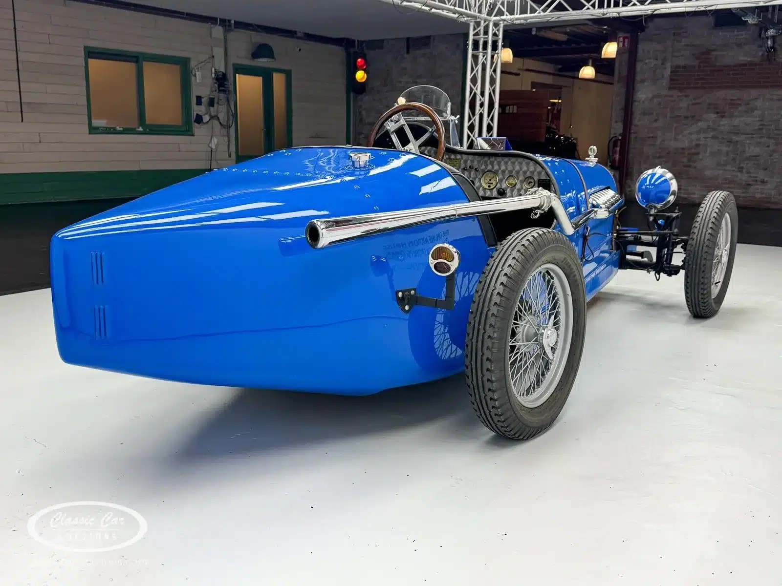 Heckansicht eines blauen Bugatti Creation Cabriolets von 1971 mit klassischen Speichenrädern, offenem Cockpit und Auspuffanlage.