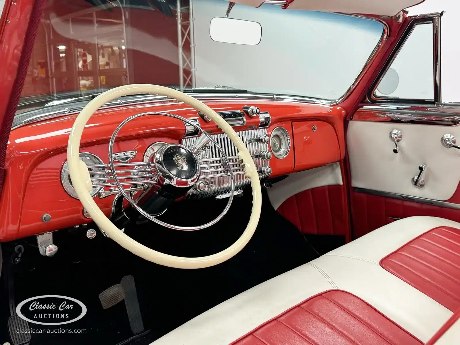 Innenansicht des roten Buick Special 40 Cabriolets von 1953 mit farblich abgestimmtem Armaturenbrett und Sitzen.