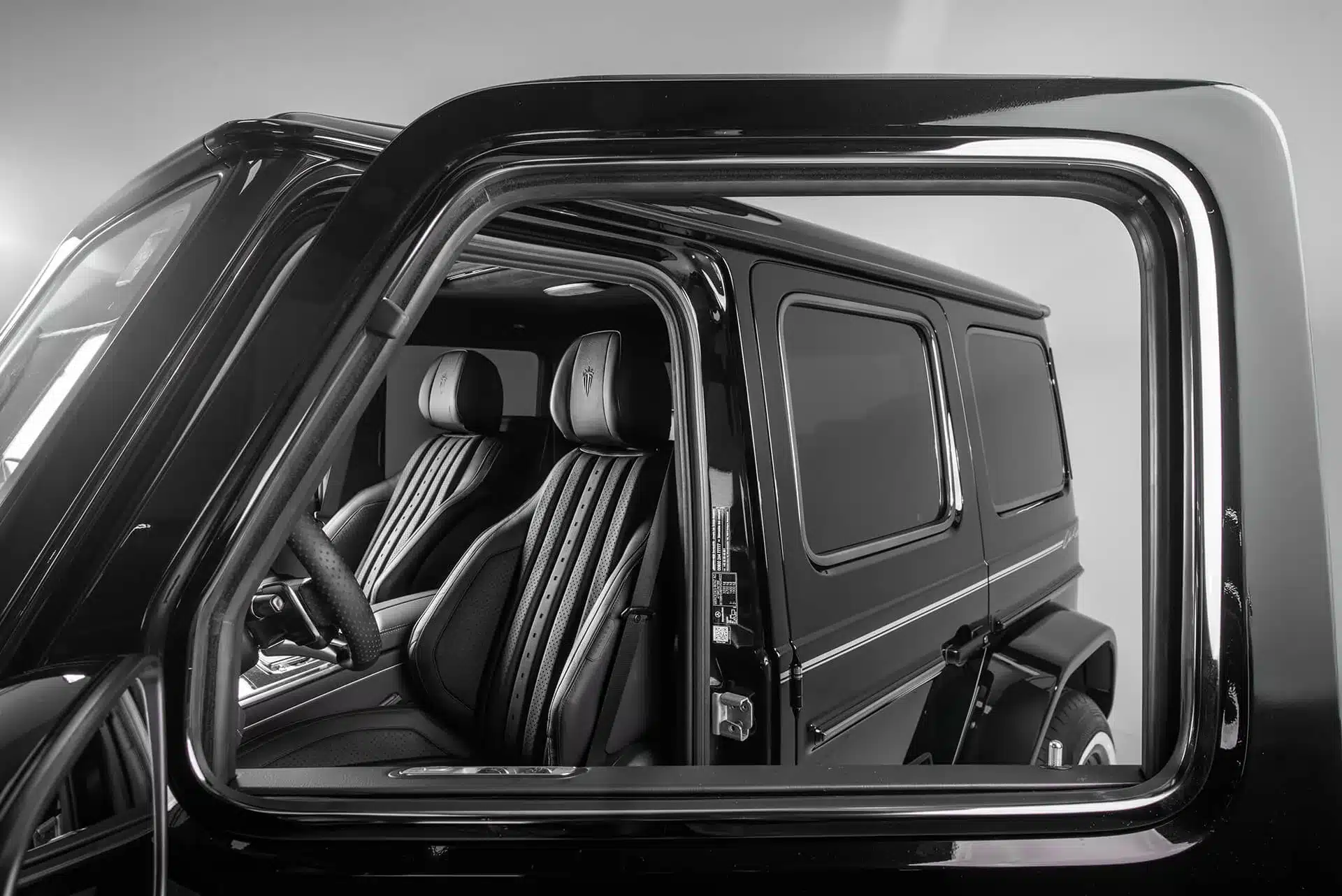 Innenraum der Carlex G63 All Black Vintage mit schwarzen Nappa-Ledersitzen, gesehen durch das geöffnete Fenster.