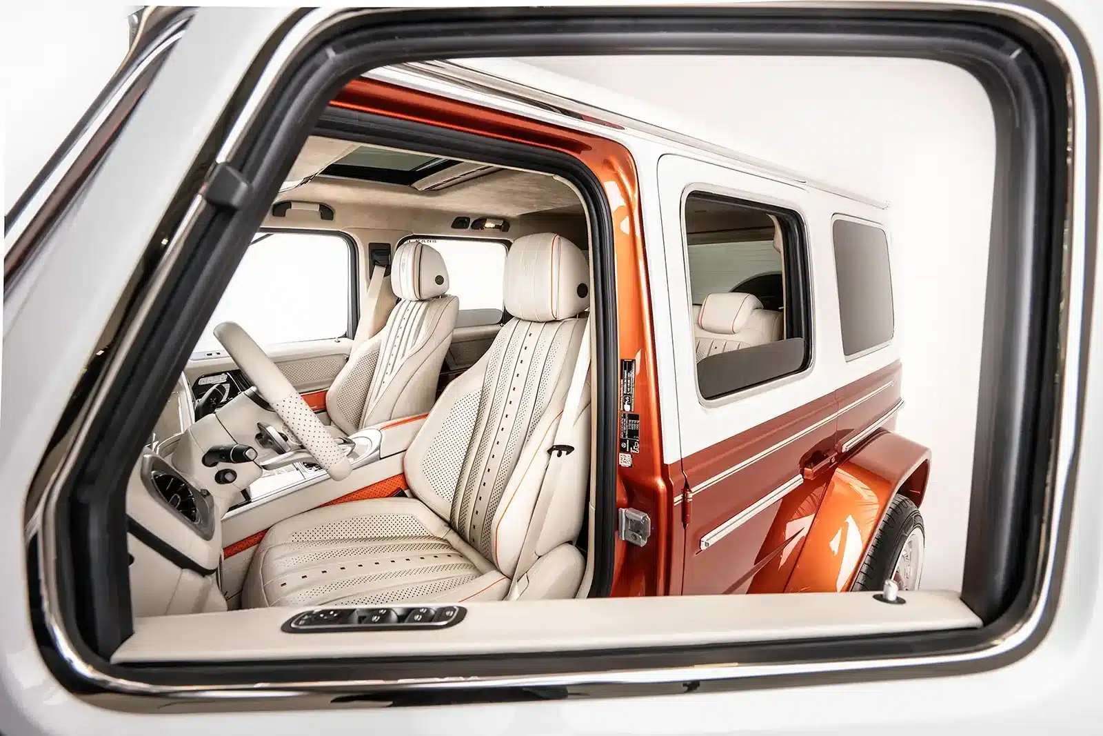 Innenraum des Carlex G63 Fiamma Vintage mit beigen Ledersitzen und orangen Designelementen, aufgenommen durch das geöffnete Fenster.