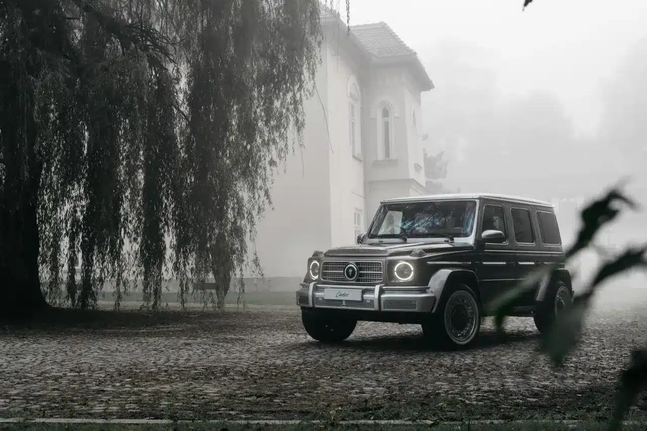 Carlex G63 Havana Vintage steht auf Kopfsteinpflaster vor einer Villa im Nebel, Baum im Vordergrund.