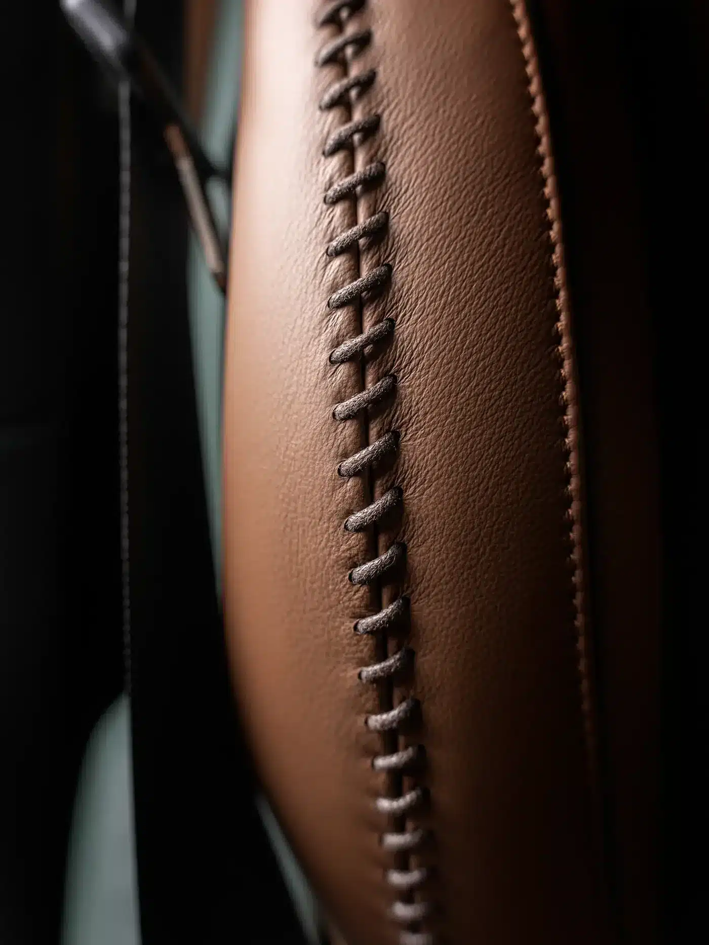 Detailansicht einer dekorativen Naht auf braunem Leder im Interieur des Carlex G63 Racing Green Vintage