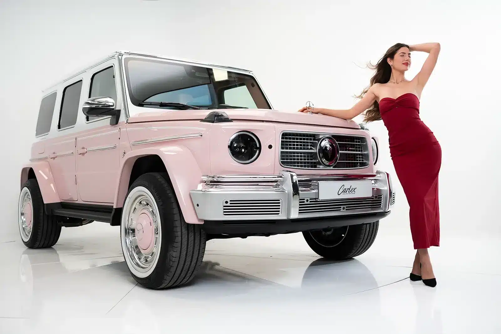 Carlex G63 Rose Vintage in zartem Rosé, ein modifizierter Mercedes-AMG G 63 mit verbreiterter Karosserie, vorgestellt in einem Fotostudio mit Modell.