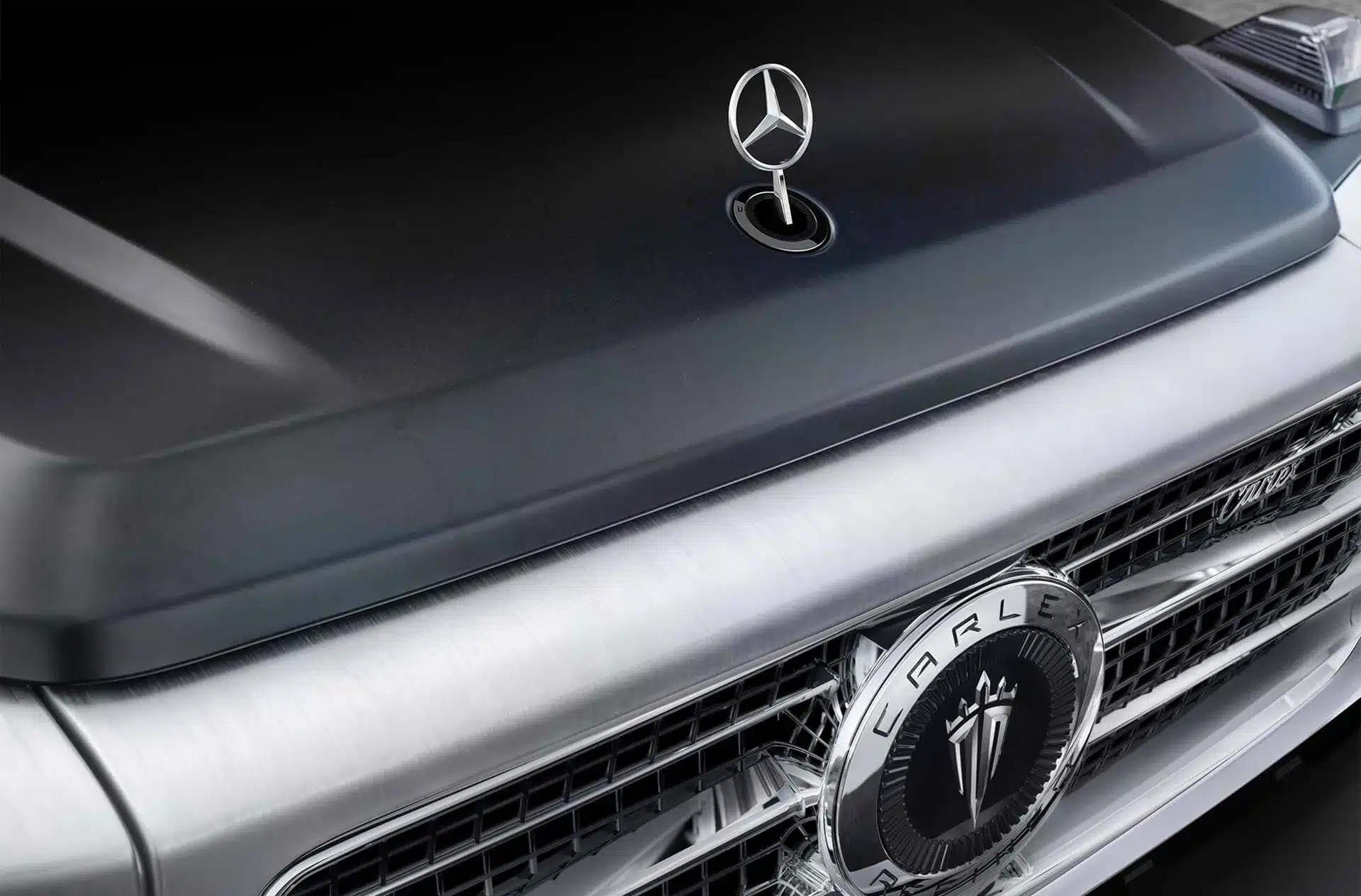 Detailaufnahme der Front der Carlex G63 Yachting Edition mit Mercedes-Stern und Carlex-Emblem auf gebürstetem Silber und schwarzer Haube