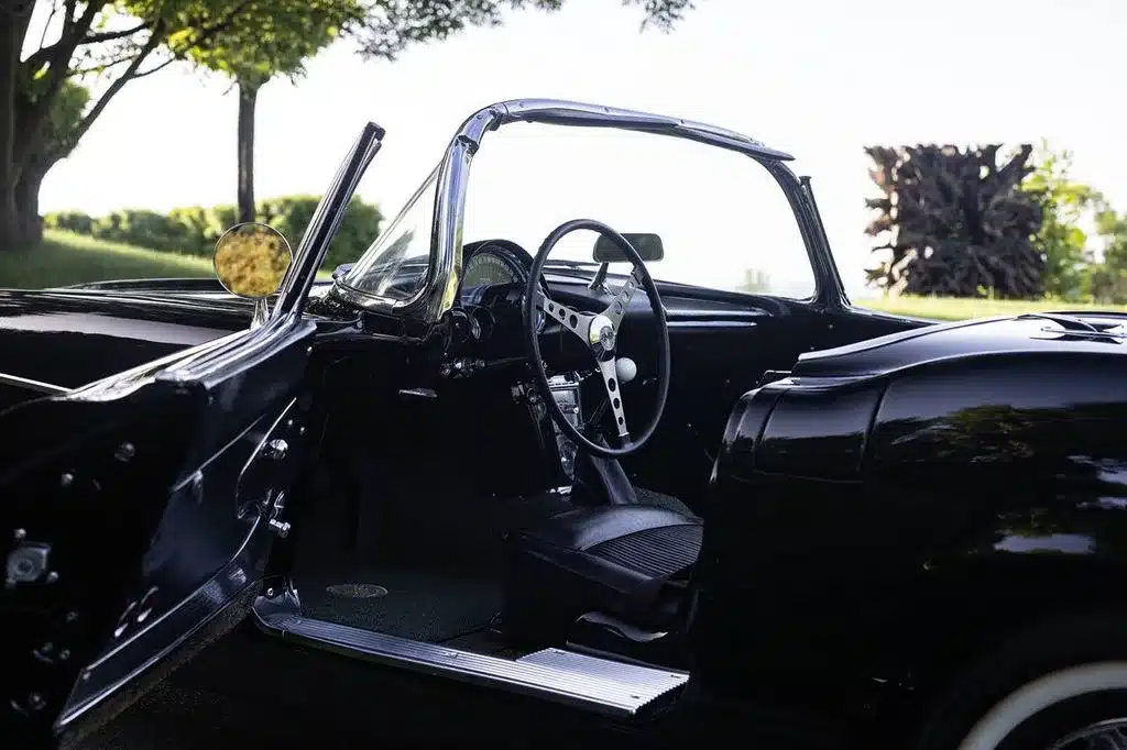 Schwarzer Innenraum einer Chevrolet Corvette C1 Cabriolet von 1961 mit Lenkrad, Schalthebel und Sitzen in Lederoptik.