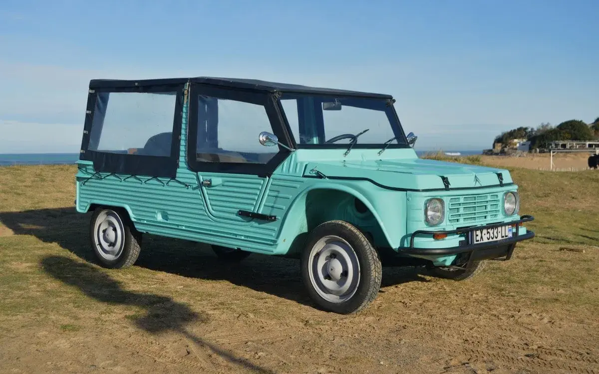Citroën Méhari von 1978 in Türkisgrün, restauriert, Cabrioverdeck, am Strand geparkt.