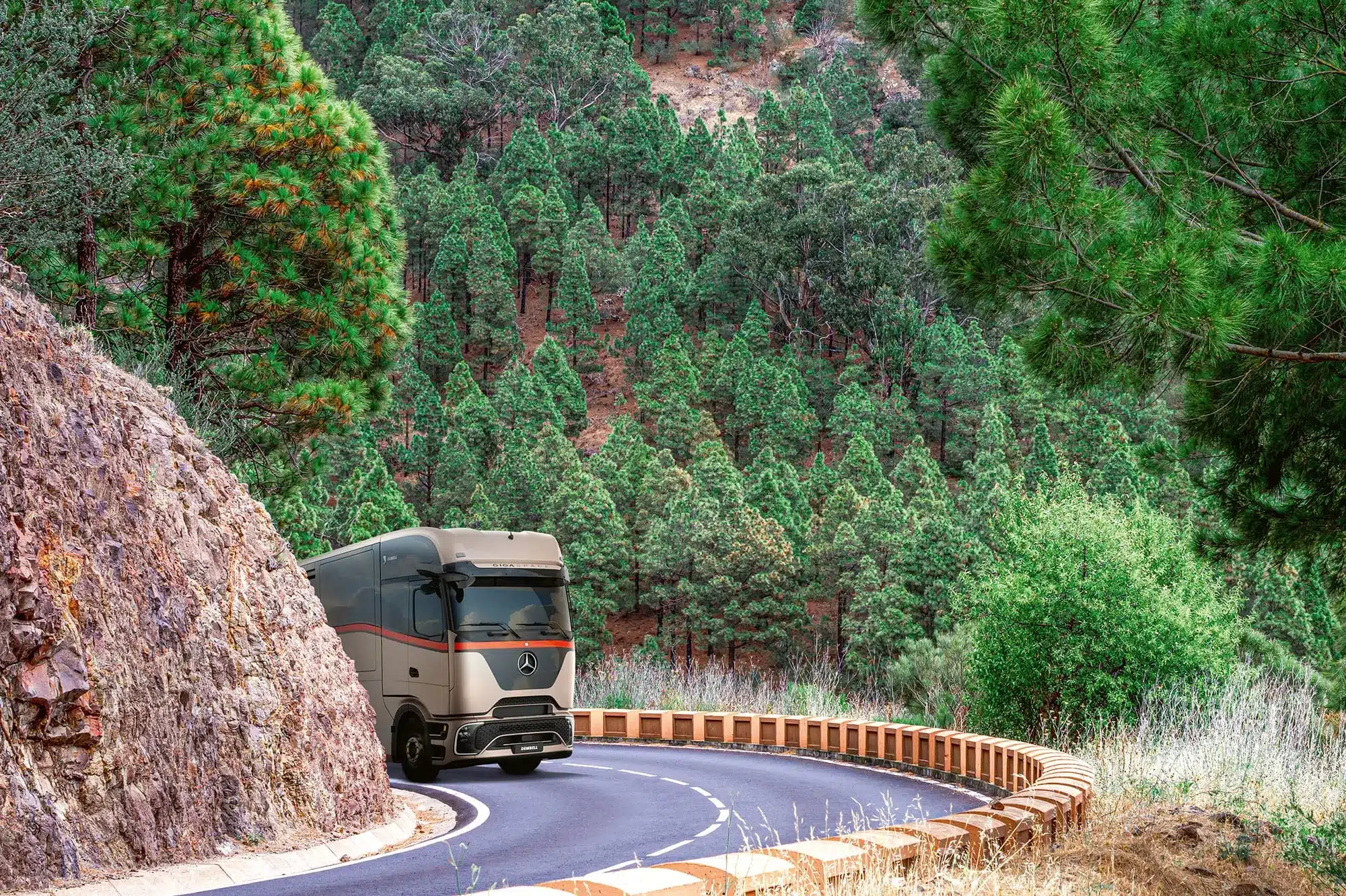 Luxuriöses Dembell Large Garage Reisemobil fährt auf einer kurvenreichen Straße durch einen dichten Kiefernwald