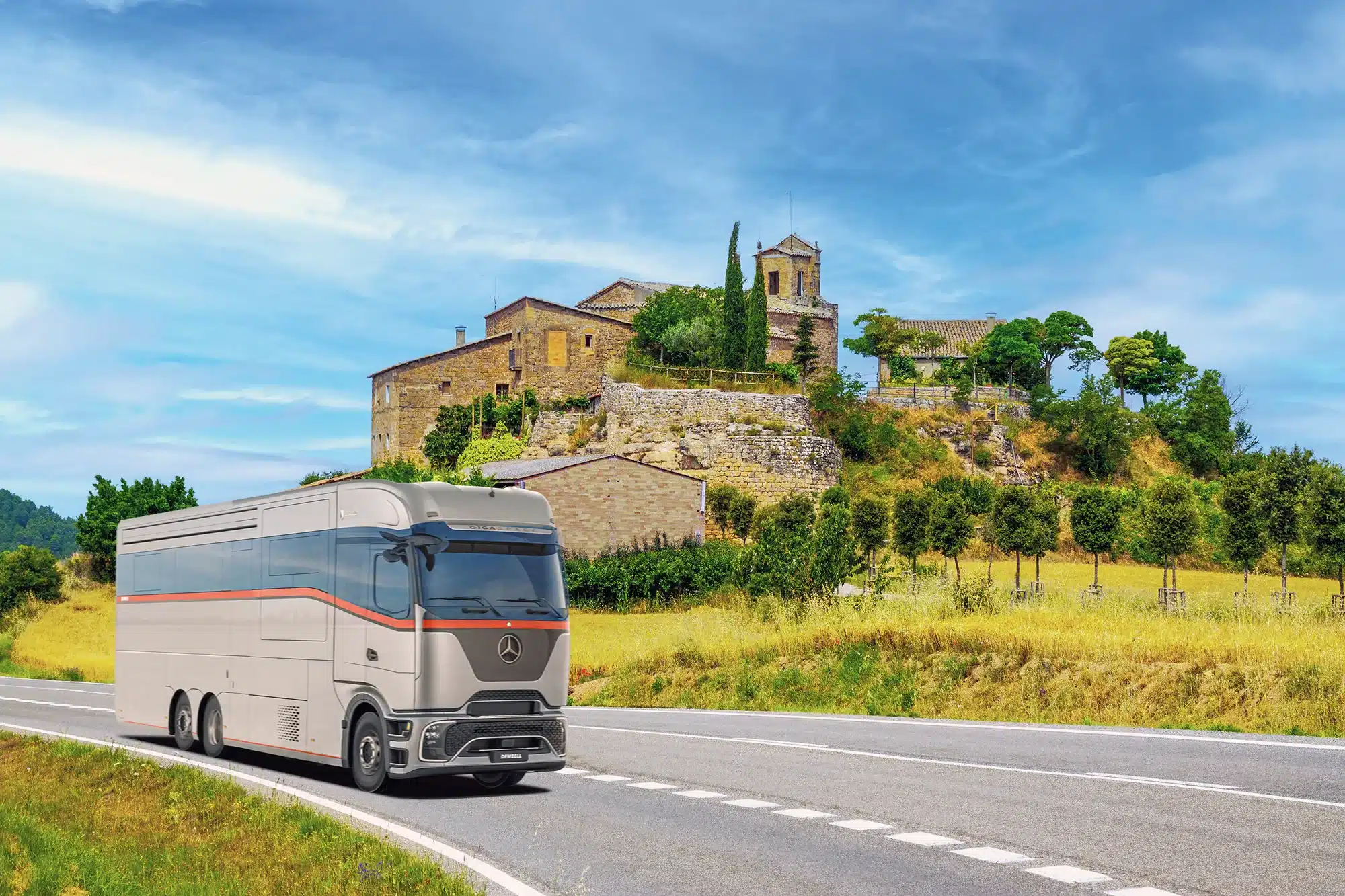 Dembell Serenity Luxus-Reisemobil auf Mercedes-Benz Actros Gigaspace fährt auf Landstraße vor historischem Gebäude.