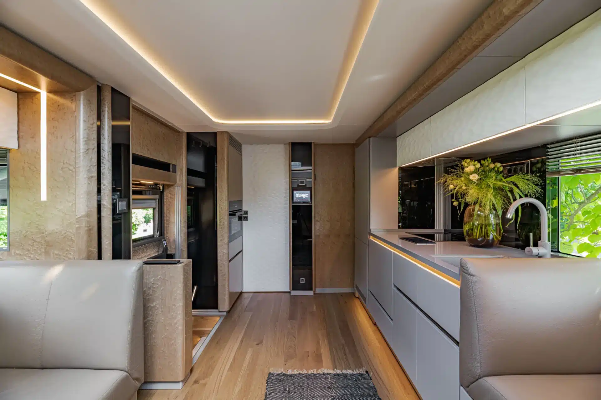 Hochwertig ausgestattete Küche und Wohnbereich im Luxus-Reisemobil Dembell Serenity, mit Holzintarsien und moderner Beleuchtung.