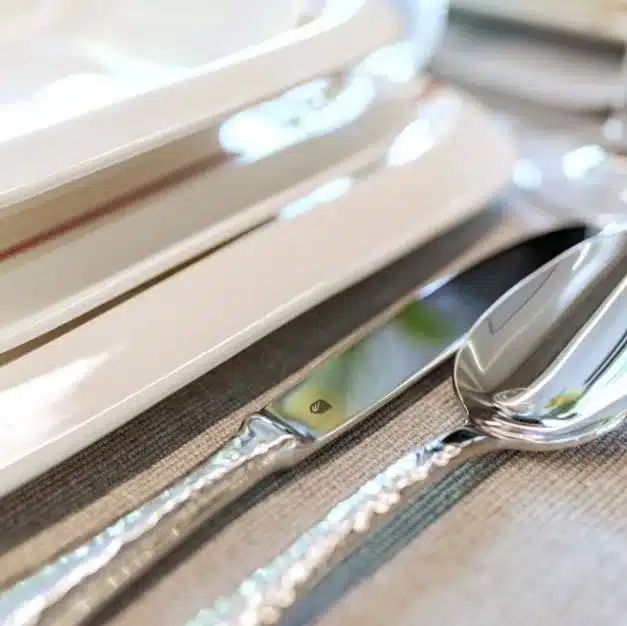 Nahaufnahme von Messer, Löffel und Tellern auf gedecktem Tisch, Detailansicht.