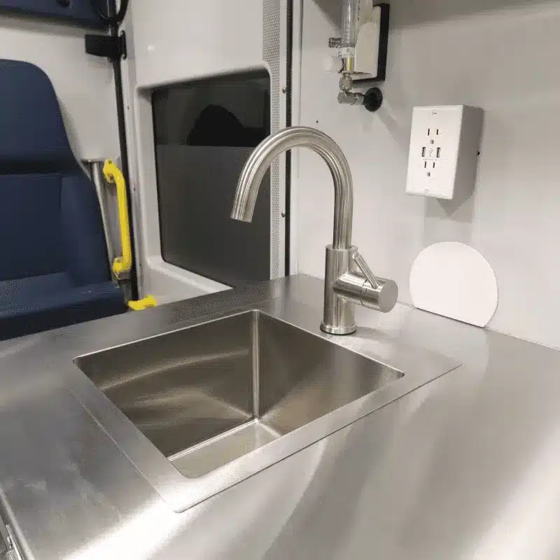 Waschbecken mit Wasserhahn und Edelstahl-Arbeitsfläche in einer mobilen Tierarztpraxis.