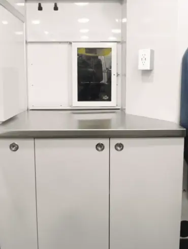 Edelstahl-Arbeitsfläche und maßgefertigte Schränke im Inneren der mobilen Tierarztpraxis auf Mercedes Sprinter Basis