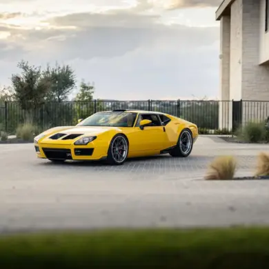 DeTomaso Pantera ADRNLN in Gelb, restauriert und getunt, steht vor einem modernen Haus bei Sonnenuntergang.