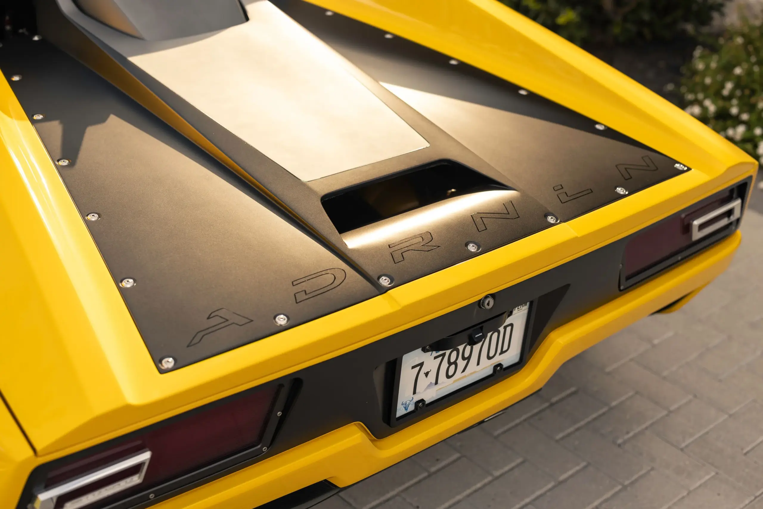 Heckpartie des gelben DeTomaso Pantera ADRNLN mit markanter Motorabdeckung und sichtbarem ADRNLN-Schriftzug.