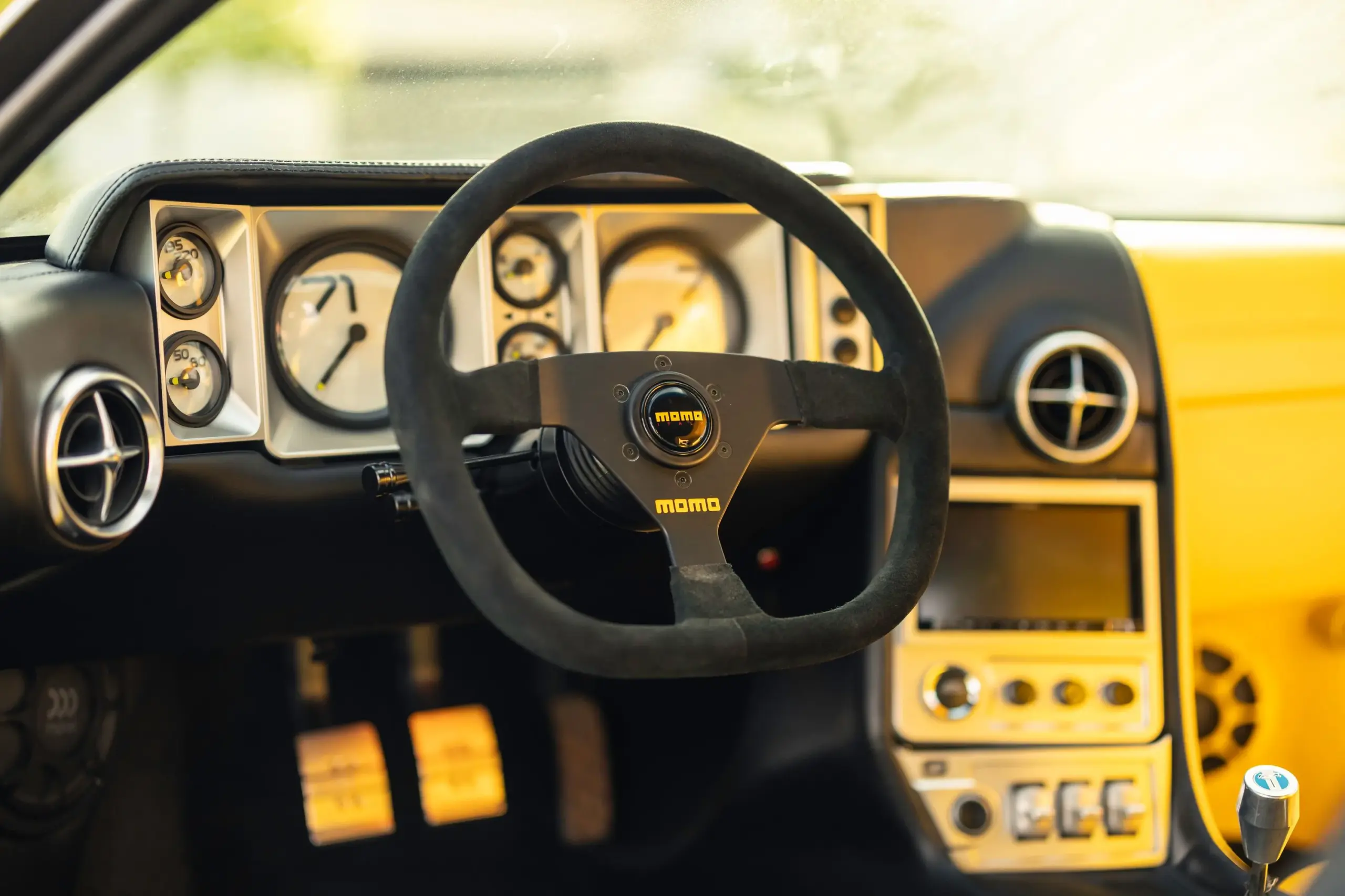 Innenraum des DeTomaso Pantera ADRNLN mit MOMO-Lenkrad, klassischen Rundinstrumenten und zeitgenössischer Mittelkonsole