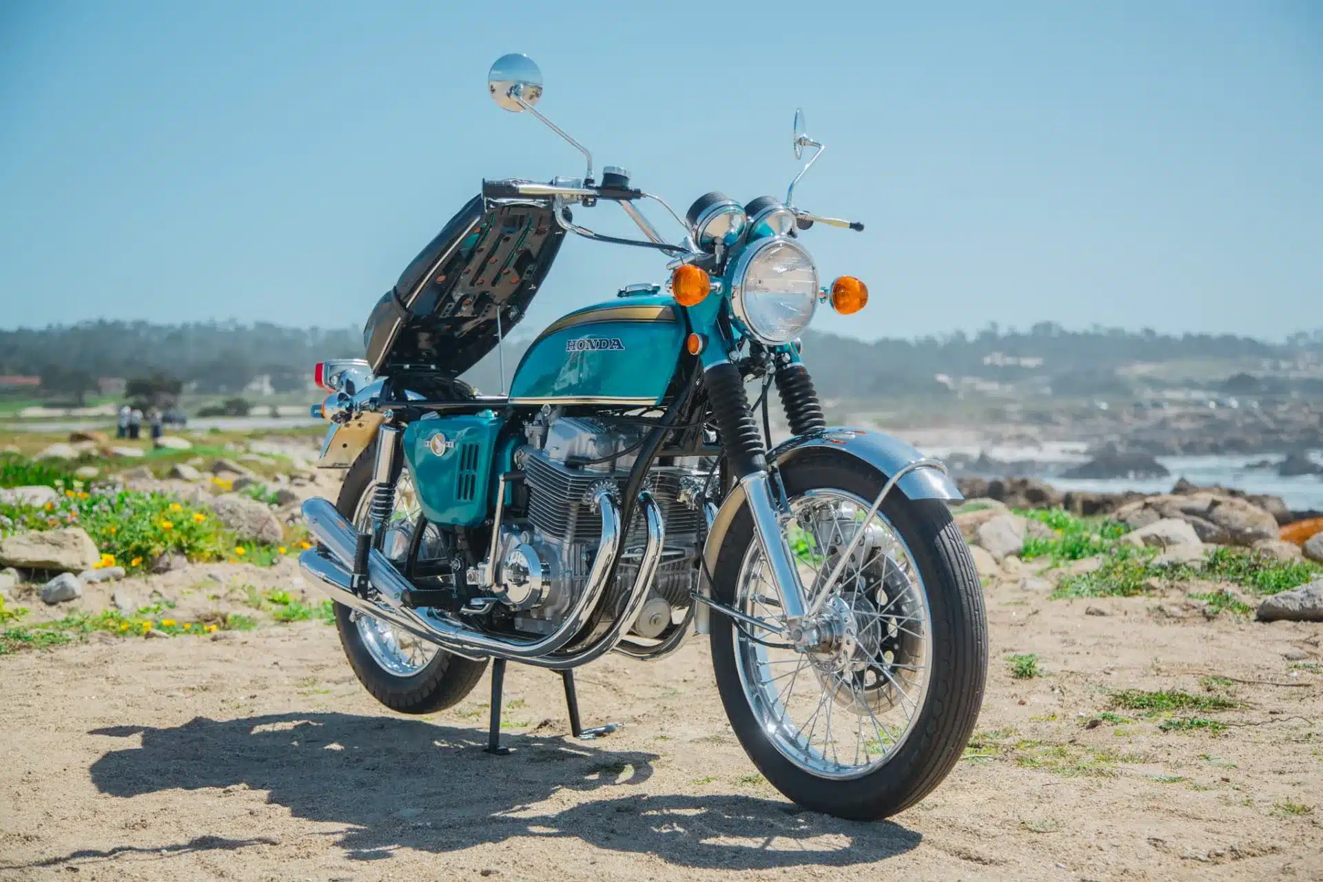 Historischer Honda CB750 Prototyp von 1968 mit hochgeklappter Sitzbank und Reihenvierzylindermotor, stehend auf sandigem Untergrund nahe dem Meer.
