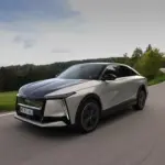 DS N°8 Elektrofahrzeug fährt dynamisch auf einer Landstraße durch eine grüne, bewaldete Landschaft.