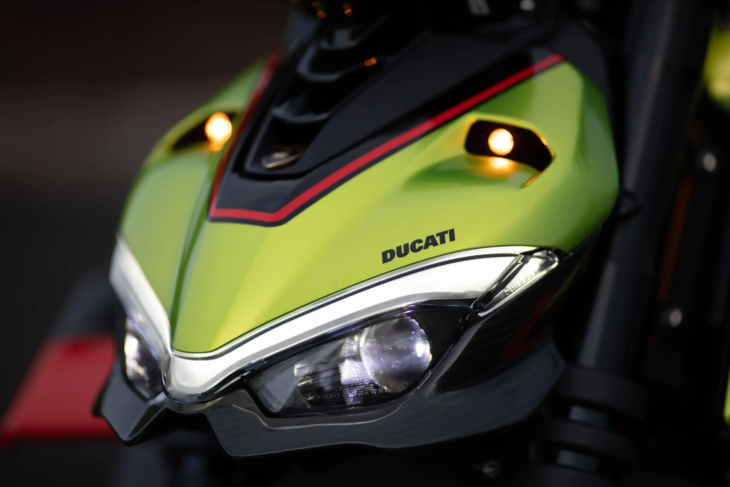 Nahaufnahme der Scheinwerfer und Frontverkleidung einer Ducati Streetfighter V4 Lamborghini mit eingeschaltetem LED-Tagfahrlicht.