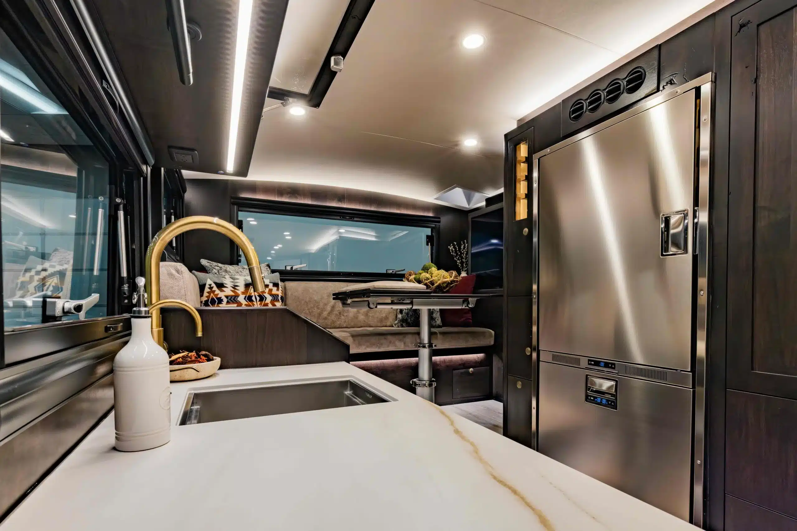 Innenraum des EarthRoamer LTX Explore mit Küchenzeile, Essecke und großem Edelstahl-Kühlschrank