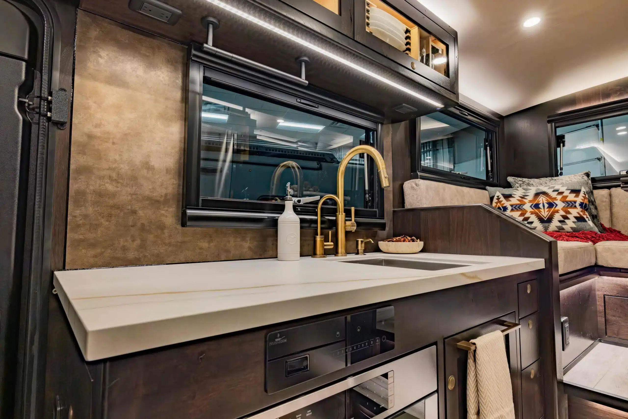 Innenansicht der modernen Küche mit goldener Armatur und Wohnbereich im EarthRoamer LTX Explore