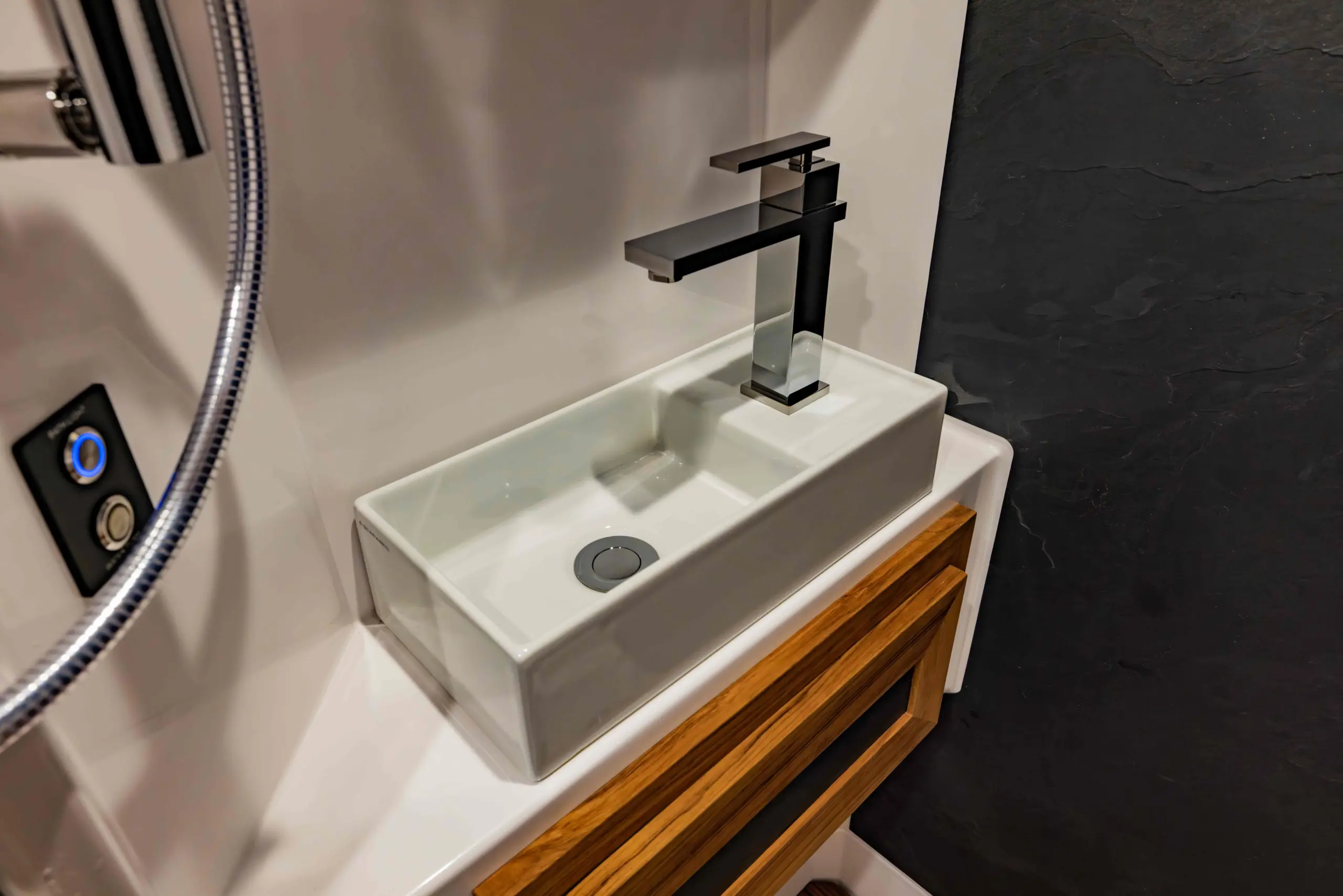 Modernes, rechteckiges Waschbecken mit Design-Armatur und Holzunterschrank in einem Expeditionsmobil-Bad