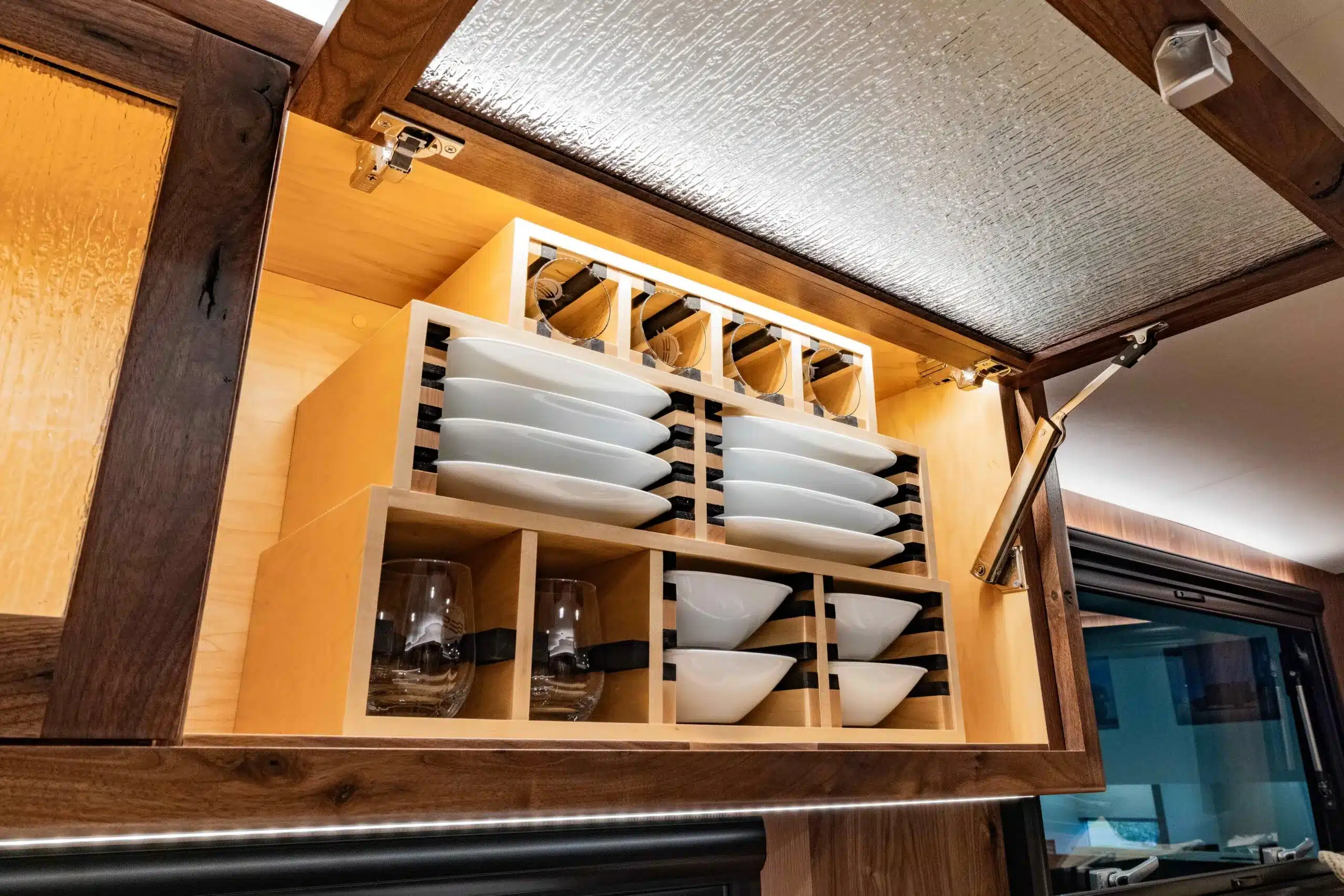 Offener Küchenschrank im EarthRoamer SX Explore mit sicher verstautem Geschirr und Gläsern in Holzfächern
