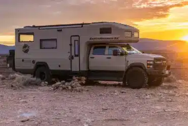 EarthRoamer SX Explore Expeditionsfahrzeug vor Sonnenuntergang in karger Landschaft.