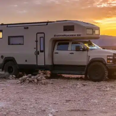 EarthRoamer SX Explore Expeditionsfahrzeug vor Sonnenuntergang in karger Landschaft.