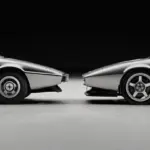 Seitenansicht von zwei Sportwagen: links ein klassischer Lotus Esprit S1, rechts die moderne Interpretation als Encor Series 1, beide in Silber vor schwarzem Hintergrund.
