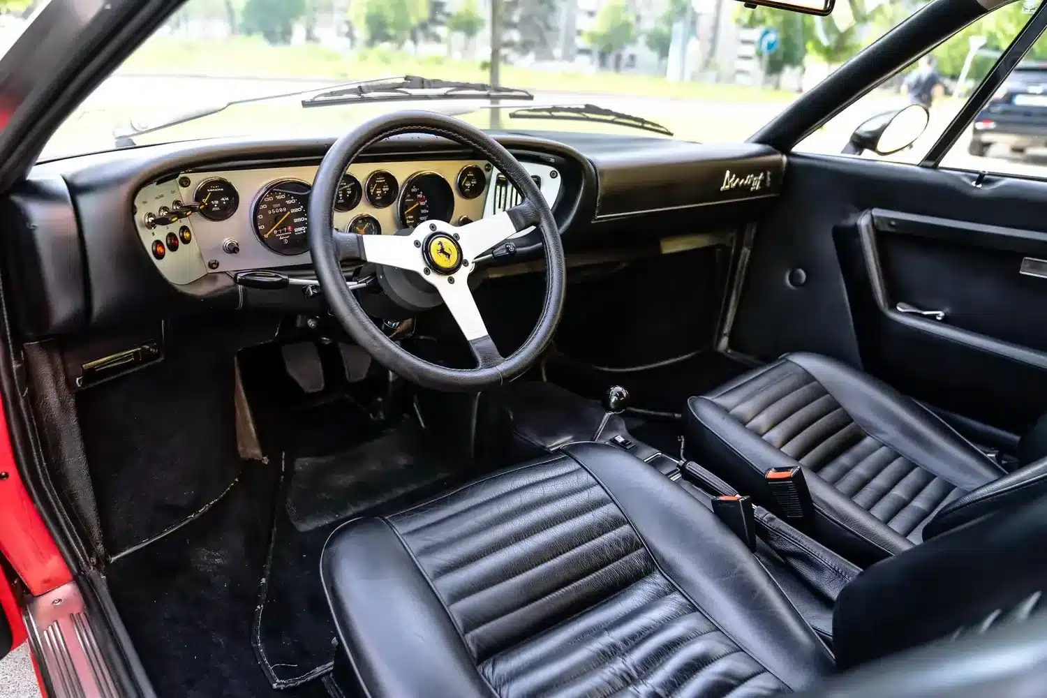 Blick in das Cockpit und auf die schwarzen Ledersitze eines Ferrari Dino 308 GT4 von 1975.