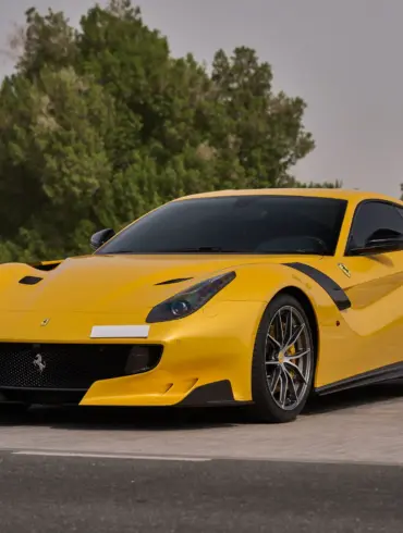 Gelber Ferrari F12 TDF mit Carbon-Details auf einem Parkplatz, sportliches Erscheinungsbild, Frontansicht.
