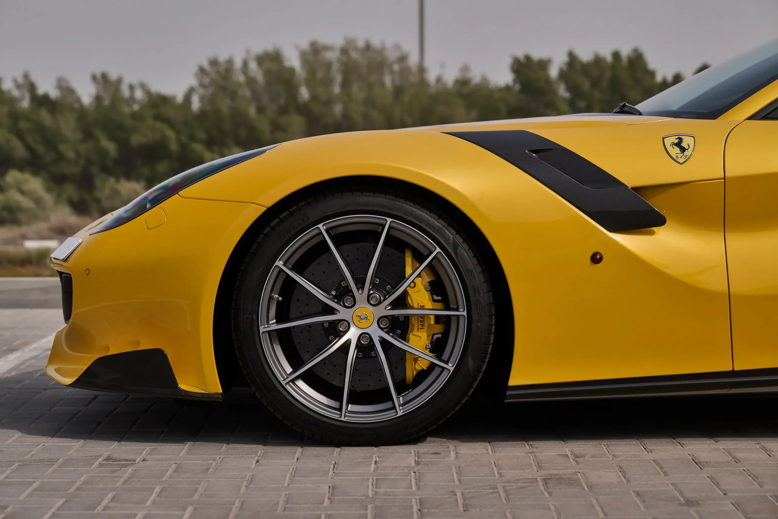 Gelber Ferrari F12 TDF mit Carbon-Kotflügelelement und Sicht auf die 20-Zoll-Felge mit gelbem Bremssattel