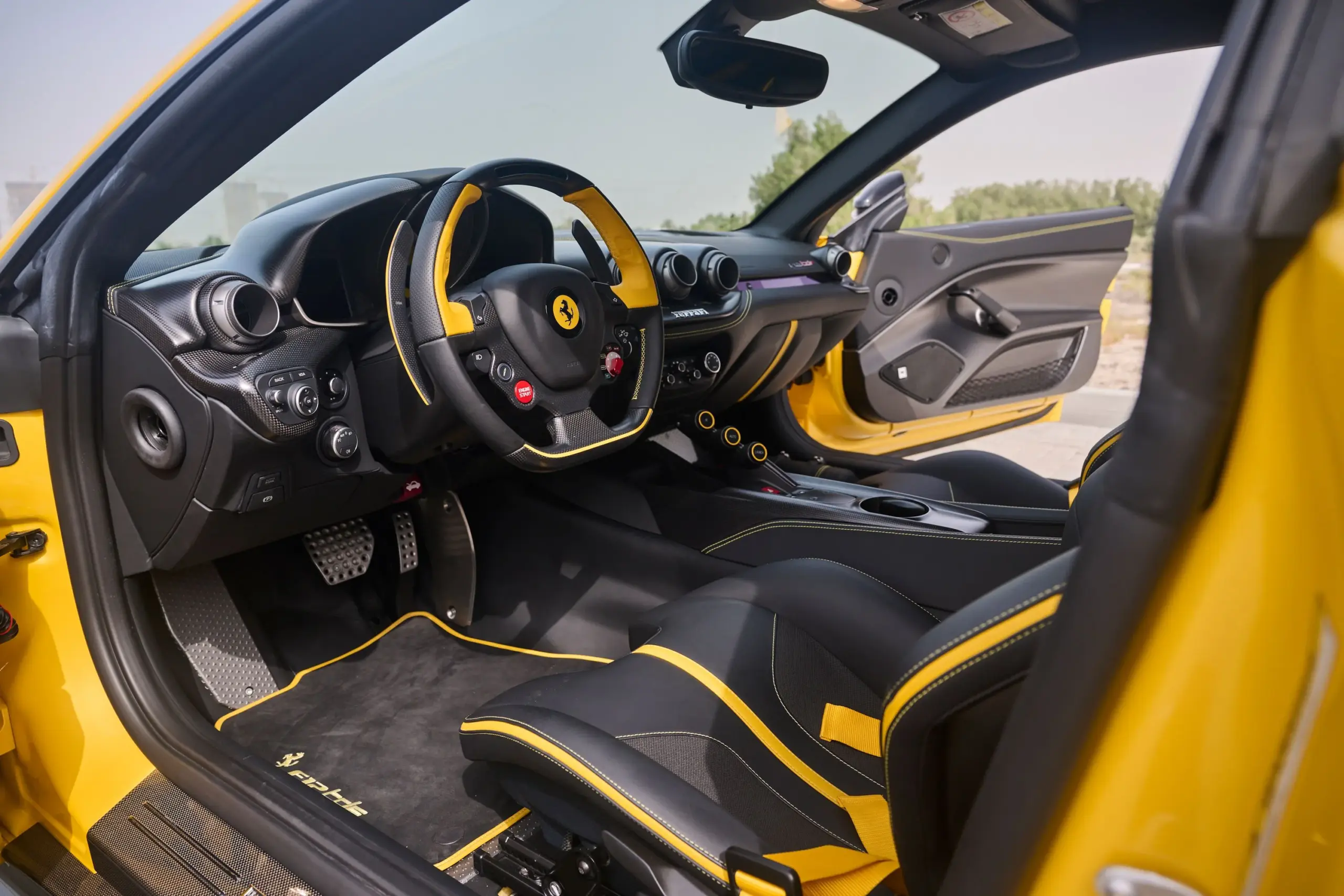 Innenraum eines Ferrari F12 TDF mit Carbon-Sportsitzen, gelben Sicherheitsgurten und Leder-Lenkrad mit gelben Akzenten