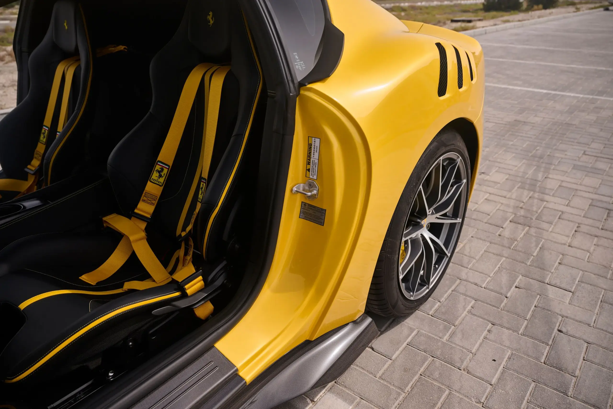 Nahaufnahme des Einstiegsbereichs mit den gelben Sicherheitsgurten und Sportsitzen eines Ferrari F12 TDF.