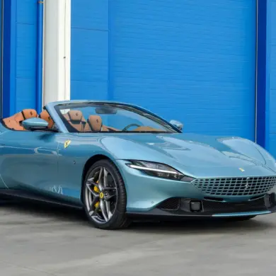 Ferrari Roma Spider 2025 in Celeste Trevi mit offenem Dach und braunem Lederinterieur, Seitenansicht.
