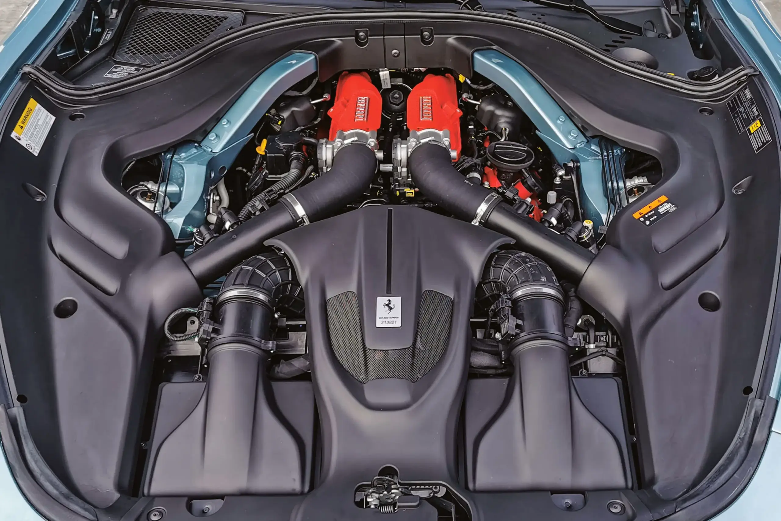 Der Motorraum des Ferrari Roma Spider 2025 mit sichtbarem V8-Biturbo-Triebwerk und roten Ventildeckeln.