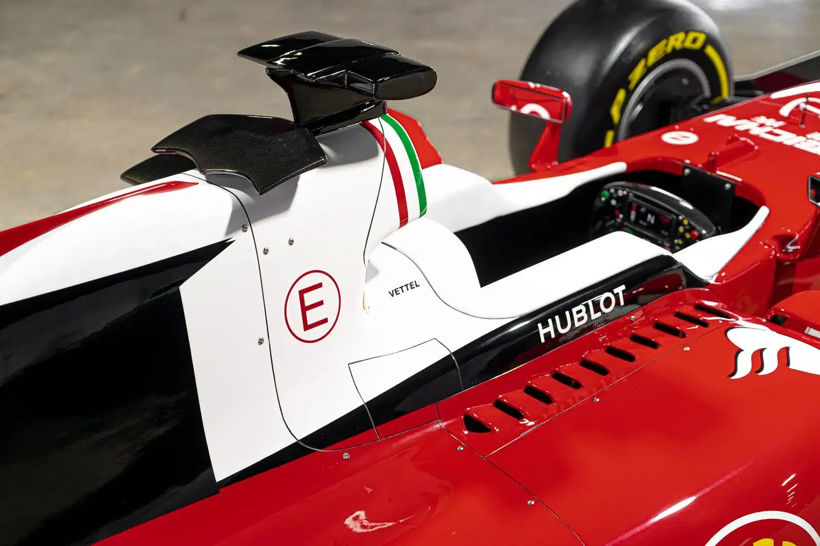 Cockpit und Airbox einer lebensgroßen Ferrari SF16-H Replika mit roten, weißen und schwarzen Karosserieteilen sowie dem Namen Vettel und Sponsorenaufdrucken.