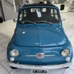 Blauer Fiat 500L Lusso von 1968 mit Faltdach, fotografiert frontal in einem hellen Showroom.