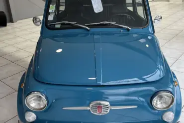 Blauer Fiat 500L Lusso von 1968 mit Faltdach, fotografiert frontal in einem hellen Showroom.